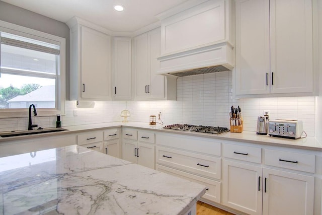 14485 S Houston St, Olathe, KS 66061 - kitchen featuring a sink, stainless steel gas cooktop, white cabinets, backsplash, and premium range hood