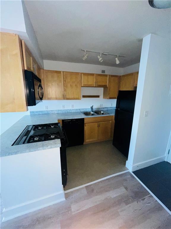 600 E 8th St Unit 11L, Kansas City, MO 64106 - kitchen featuring black appliances, a sink, light countertops, light wood finished floors, and baseboards
