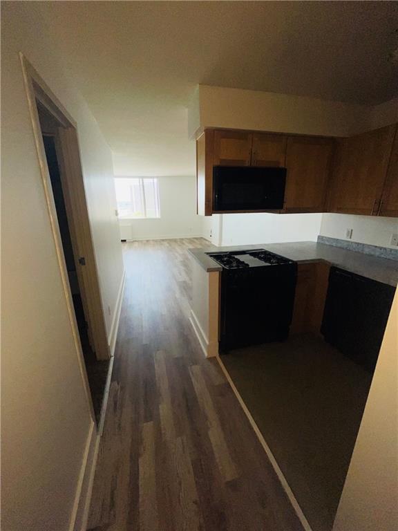 600 E 8th St Unit 11L, Kansas City, MO 64106 - kitchen featuring black microwave, dark wood-style floors, baseboards, brown cabinetry, and cooktop