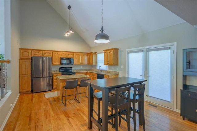 7500 N Oakland Ave, Kansas City, MO 64158 - kitchen featuring black appliances, high vaulted ceiling, a kitchen island, light wood finished floors, and decorative light fixtures