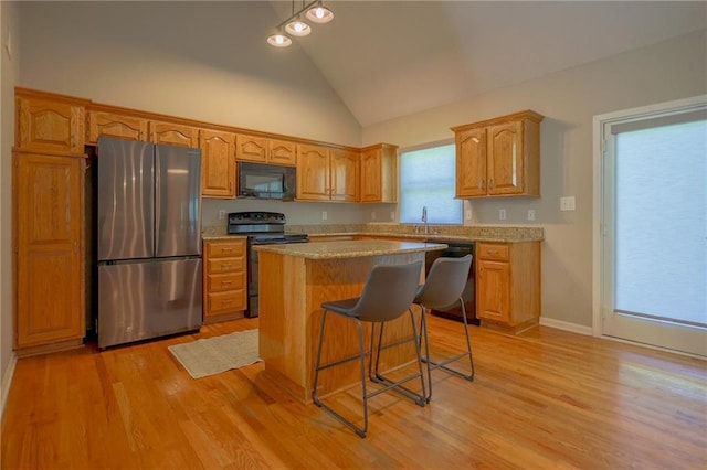 7500 N Oakland Ave, Kansas City, MO 64158 - kitchen with black appliances, light countertops, a center island, a kitchen bar, and light wood-type flooring