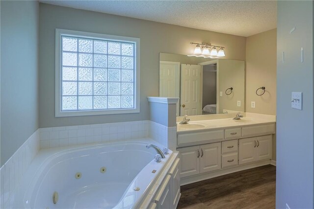 7500 N Oakland Ave, Kansas City, MO 64158 - bathroom with healthy amount of natural light, double vanity, a tub with jets, wood finished floors, and a textured ceiling