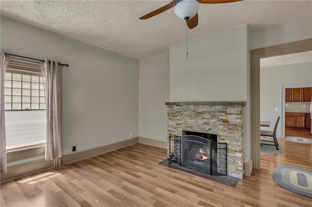 228 S Elm St, Ottawa, KS 66067 - unfurnished living room featuring wood finished floors, a ceiling fan, a fireplace, a textured ceiling, and baseboards
