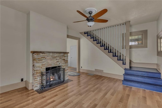 228 S Elm St, Ottawa, KS 66067 - unfurnished living room with a fireplace, stairs, light wood-style floors, and ceiling fan