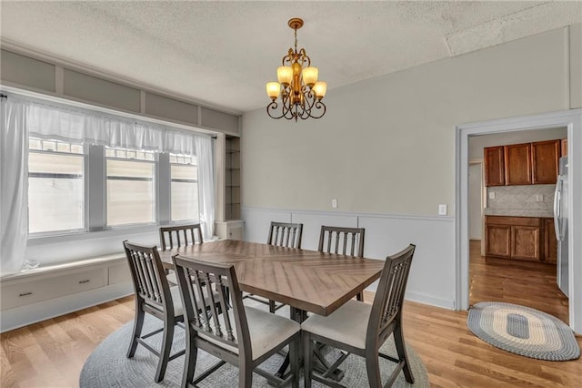 228 S Elm St, Ottawa, KS 66067 - dining room featuring a chandelier, light wood-type flooring, and a textured ceiling