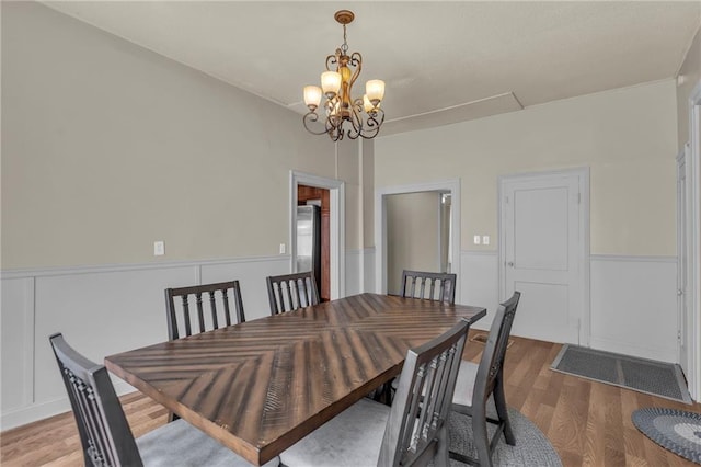 228 S Elm St, Ottawa, KS 66067 - dining room featuring wood finished floors, a chandelier, a wainscoted wall, attic access, and a decorative wall