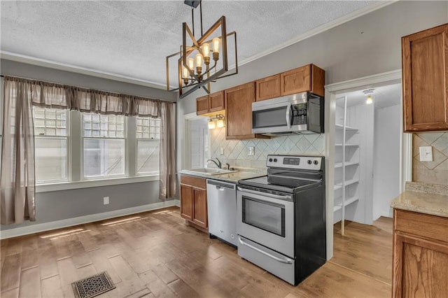 228 S Elm St, Ottawa, KS 66067 - kitchen featuring appliances with stainless steel finishes, brown cabinetry, a textured ceiling, tasteful backsplash, and wood finished floors