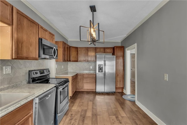 228 S Elm St, Ottawa, KS 66067 - kitchen with appliances with stainless steel finishes, ornamental molding, light countertops, backsplash, and wood finished floors