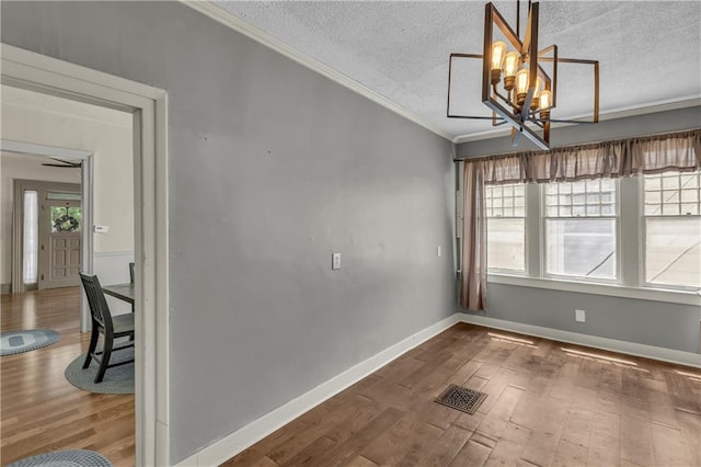 228 S Elm St, Ottawa, KS 66067 - empty room featuring ornamental molding, wood finished floors, plenty of natural light, a textured ceiling, and a chandelier