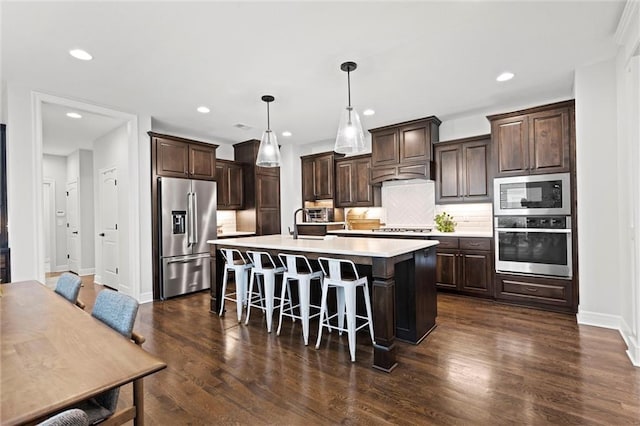 3205 SW Mary St, Lees Summit, MO 64081 - kitchen with stainless steel appliances, dark brown cabinetry, light countertops, a kitchen island with sink, and recessed lighting