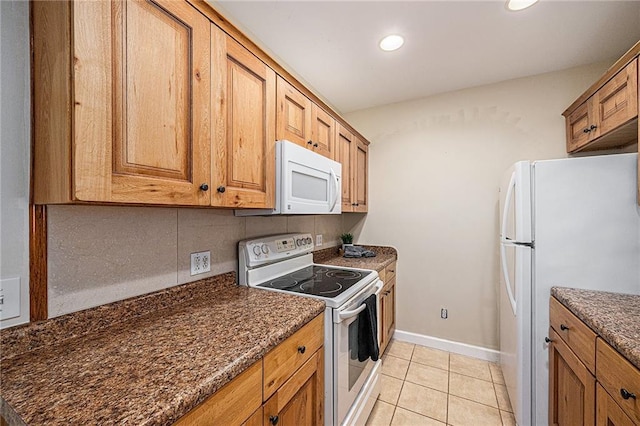 614 S 7th St, Atchison, KS 66002 - kitchen with white appliances, dark countertops, tasteful backsplash, light tile patterned floors, and brown cabinetry
