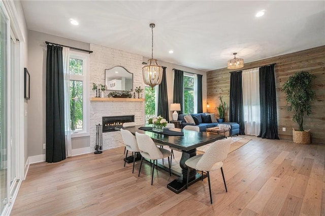 4112 W 156th St, Overland Park, KS 66224 - dining room featuring light wood-style flooring, a chandelier, a stone fireplace, recessed lighting, and wooden walls