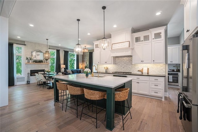 4112 W 156th St, Overland Park, KS 66224 - kitchen featuring appliances with stainless steel finishes, a sink, decorative backsplash, light wood-style floors, and a breakfast bar