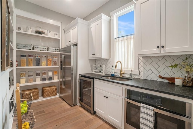 4112 W 156th St, Overland Park, KS 66224 - kitchen with appliances with stainless steel finishes, a sink, wine cooler, dark countertops, and white cabinetry
