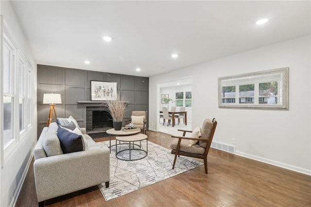 618 E 108th Ter, Kansas City, MO 64131 - living area with wood finished floors, baseboards, a fireplace with raised hearth, and recessed lighting