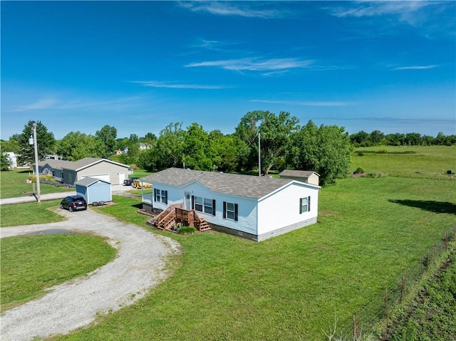 516 E 614th St, Girard, KS 66743 - manufactured / mobile home featuring a front lawn, driveway, an outdoor structure, and roof with shingles