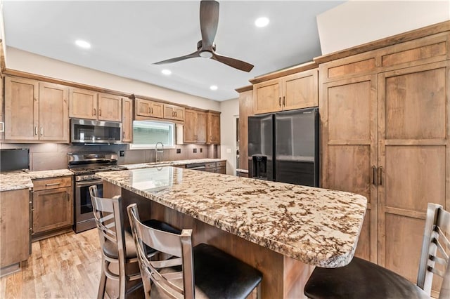 1105 S Gordon St, Concordia, MO 64020 - kitchen featuring appliances with stainless steel finishes, a sink, a breakfast bar, light stone counters, and recessed lighting