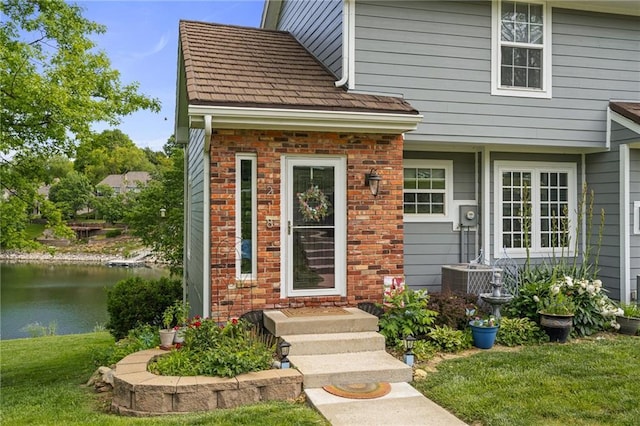 218 NE Bayview Dr, Lees Summit, MO 64064 - doorway to property featuring a water view, a lawn, and central air condition unit