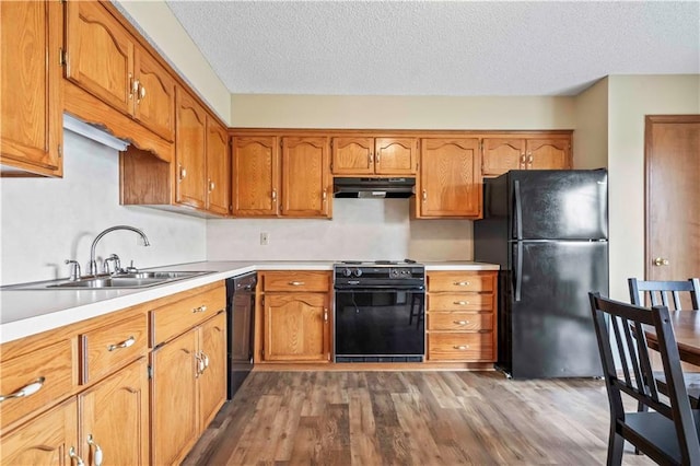 1109 Jeff Cir, Paola, KS 66071 - kitchen with black appliances, under cabinet range hood, a sink, wood finished floors, and brown cabinets