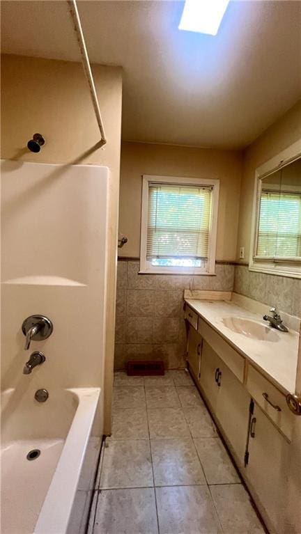 1445 E 77th St, Kansas City, MO 64131 - full bathroom featuring tile patterned floors, vanity, tile walls, shower / bathtub combination, and a wainscoted wall