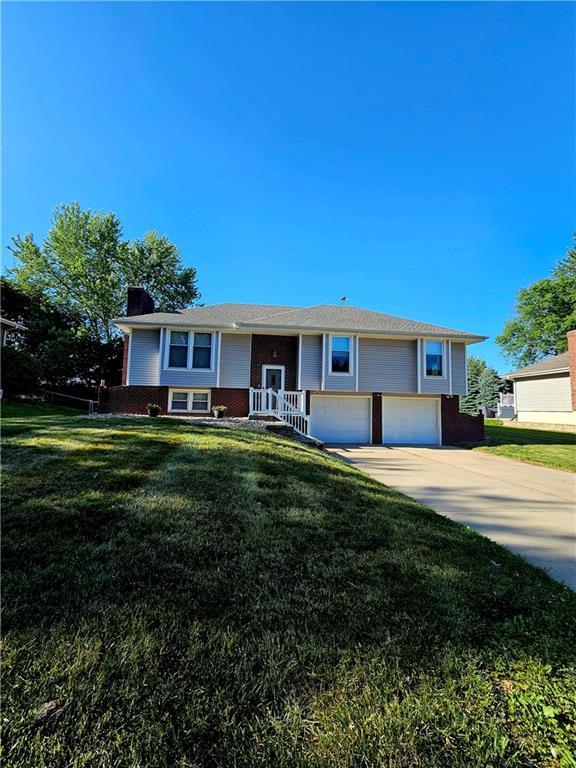 4513 Alpha Ln, Saint Joseph, MO 64506 - split foyer home featuring brick siding, a chimney, an attached garage, and a front lawn