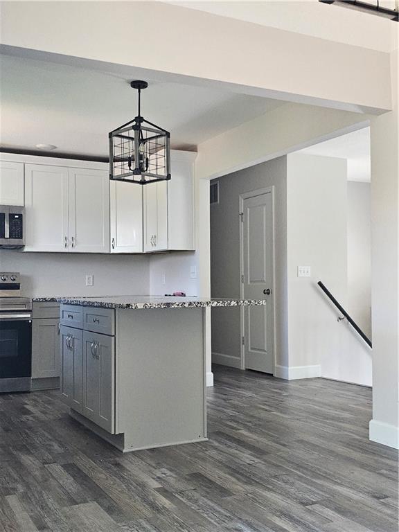 4513 Alpha Ln, Saint Joseph, MO 64506 - kitchen with appliances with stainless steel finishes, dark wood-style floors, white cabinetry, a chandelier, and baseboards