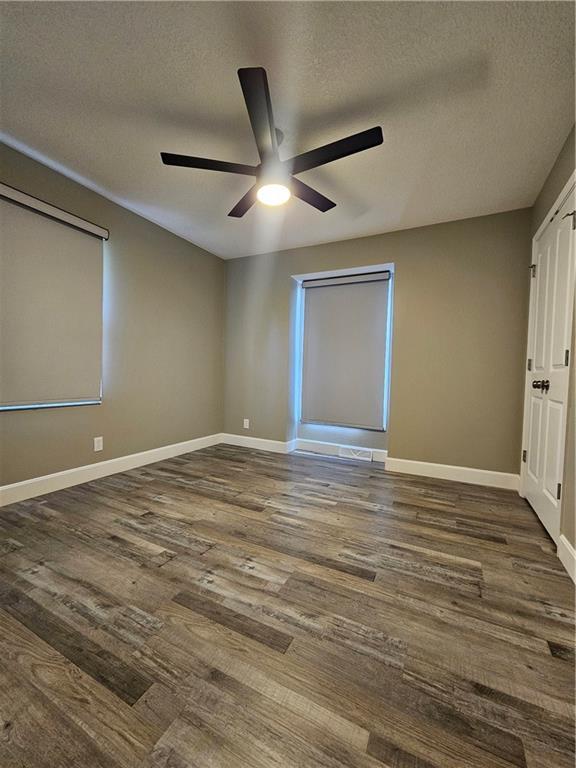 4513 Alpha Ln, Saint Joseph, MO 64506 - unfurnished bedroom with dark wood-type flooring, baseboards, ceiling fan, and a textured ceiling