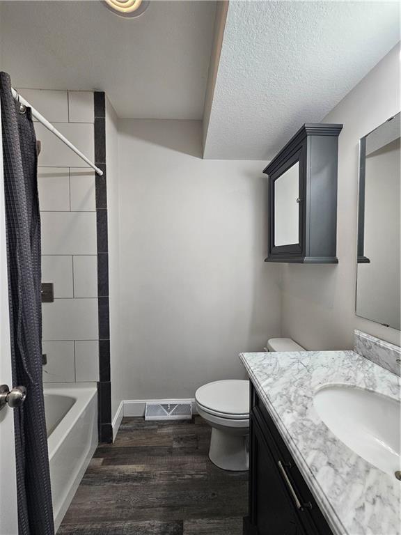 4513 Alpha Ln, Saint Joseph, MO 64506 - full bath with wood finished floors, vanity, toilet, shower / tub combo, and baseboards