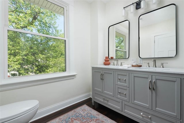 1795 S Norwood Ave, Independence, MO 64052 - full bathroom featuring wood finished floors, baseboards, toilet, and double vanity