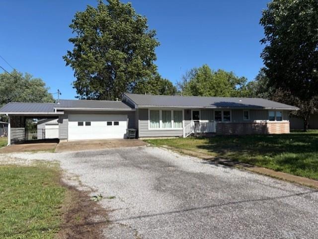 22025 Ness Rd, Parsons, KS 67357 - ranch-style house with an attached garage, driveway, a front yard, and a carport