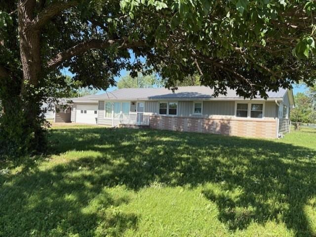 22025 Ness Rd, Parsons, KS 67357 - view of front of house featuring a garage, a front yard, brick siding, and board and batten siding