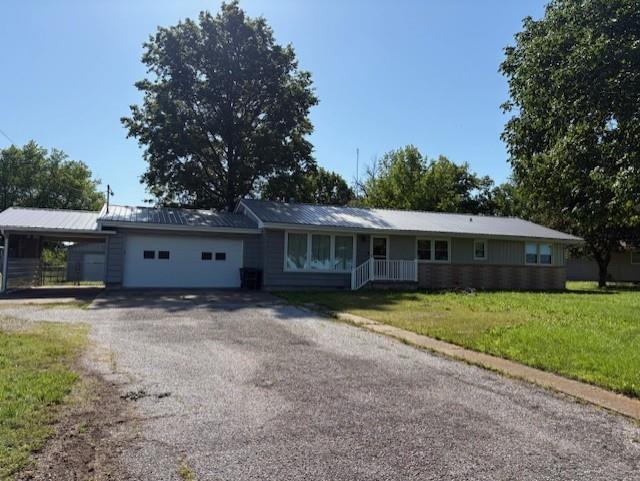 22025 Ness Rd, Parsons, KS 67357 - single story home with an attached garage, a carport, a front yard, and asphalt driveway