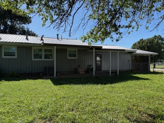 22025 Ness Rd, Parsons, KS 67357 - rear view of house featuring board and batten siding, a yard, and central AC