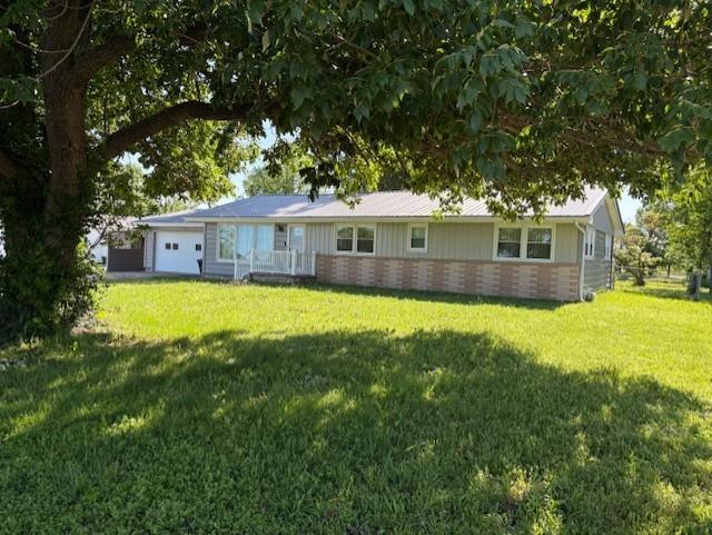 22025 Ness Rd, Parsons, KS 67357 - back of property with a garage, a yard, and brick siding