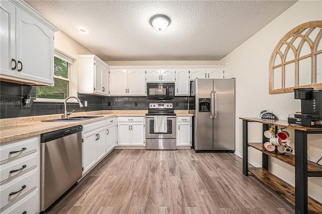 5862 SW Reed Ln, Trimble, MO 64492 - kitchen with appliances with stainless steel finishes, a sink, light wood-style flooring, a textured ceiling, and white cabinets