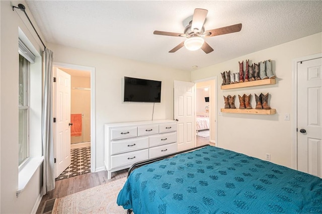5862 SW Reed Ln, Trimble, MO 64492 - bedroom featuring light wood finished floors, ensuite bathroom, ceiling fan, baseboards, and a textured ceiling
