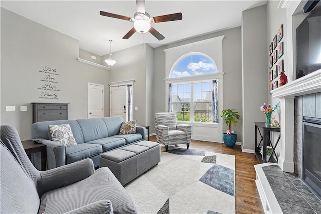 1106 E 14th St, Kearney, MO 64060 - living room featuring a tiled fireplace, a ceiling fan, wood finished floors, a high ceiling, and baseboards