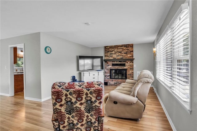 1018 S Elm St, Ottawa, KS 66067 - living room with light wood-type flooring, plenty of natural light, a brick fireplace, and baseboards