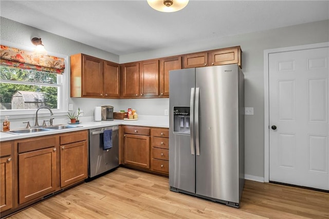 1018 S Elm St, Ottawa, KS 66067 - kitchen featuring appliances with stainless steel finishes, a sink, brown cabinetry, and light wood-style flooring