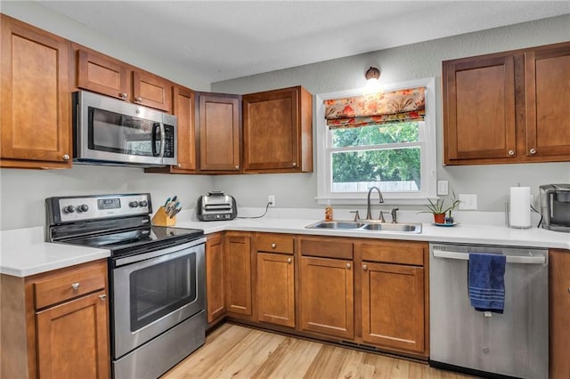 1018 S Elm St, Ottawa, KS 66067 - kitchen with stainless steel appliances, a sink, light countertops, light wood finished floors, and brown cabinetry
