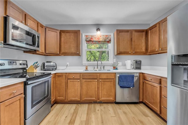 1018 S Elm St, Ottawa, KS 66067 - kitchen featuring stainless steel appliances, a sink, light wood-style flooring, brown cabinetry, and light countertops
