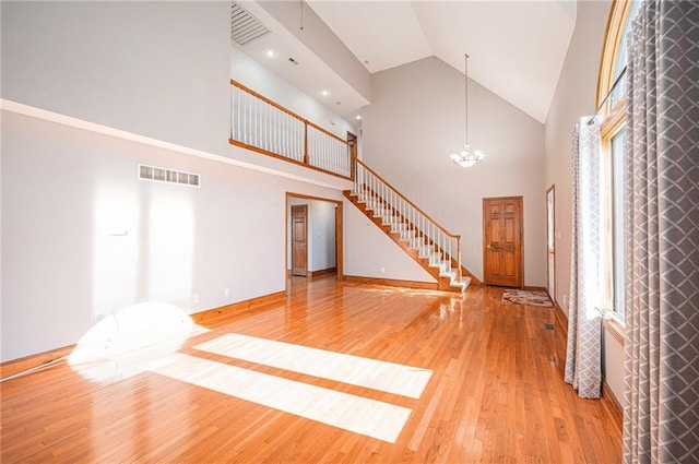 3304 Tepee Ct, Independence, MO 64057 - unfurnished living room with high vaulted ceiling, stairway, a chandelier, light wood-style flooring, and healthy amount of natural light