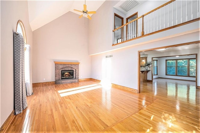 3304 Tepee Ct, Independence, MO 64057 - unfurnished living room featuring wood finished floors, high vaulted ceiling, a brick fireplace, ceiling fan, and baseboards