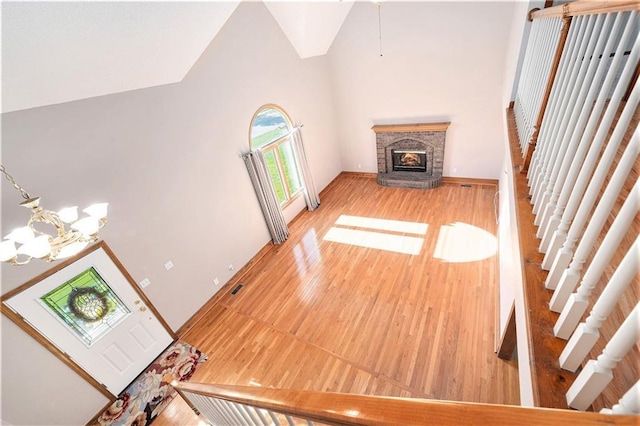 3304 Tepee Ct, Independence, MO 64057 - unfurnished living room with a chandelier, high vaulted ceiling, a glass covered fireplace, stairs, and light wood-type flooring