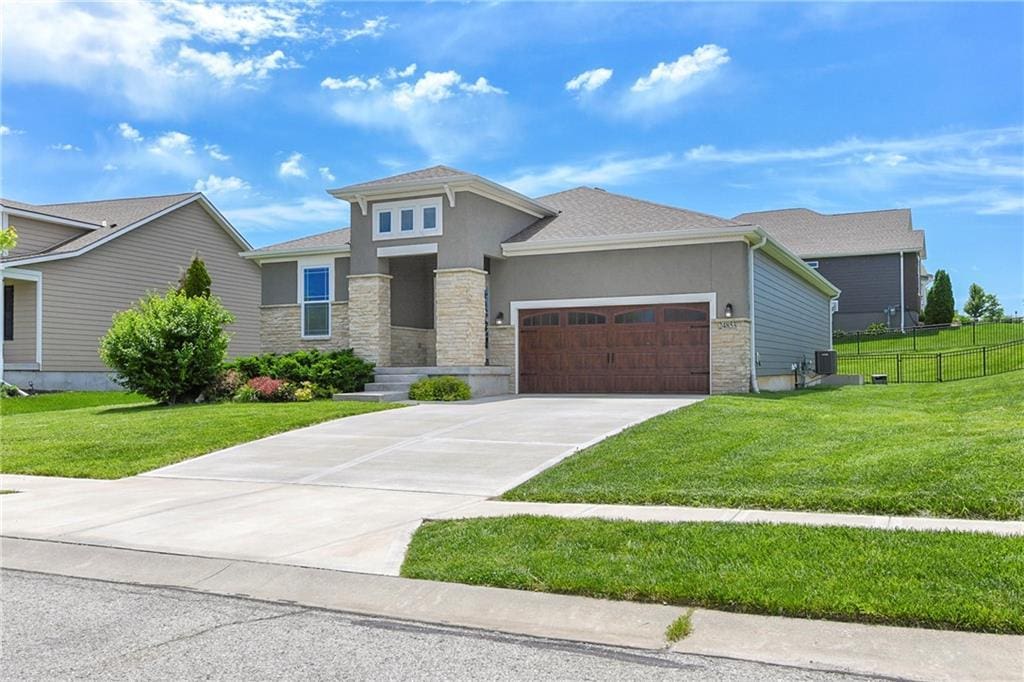 24853 W 144th St, Olathe, KS 66061 - prairie-style home featuring stone siding, an attached garage, stucco siding, driveway, and central AC