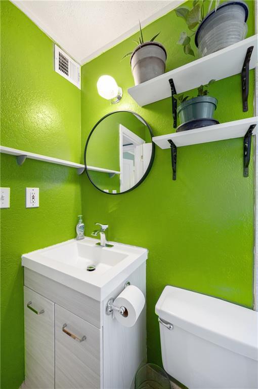 11410 W 68th Ter, Shawnee, KS 66203 - half bath featuring toilet, vanity, and a textured wall