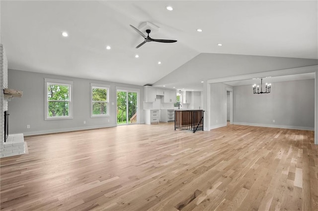 308 N 22nd St, Leavenworth, KS 66048 - unfurnished living room with a fireplace, a chandelier, ceiling fan, lofted ceiling, and light wood-type flooring