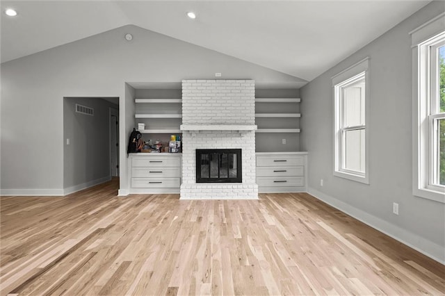 308 N 22nd St, Leavenworth, KS 66048 - unfurnished living room featuring vaulted ceiling, built in shelves, a brick fireplace, light wood-type flooring, and baseboards