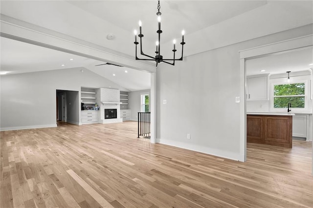 308 N 22nd St, Leavenworth, KS 66048 - unfurnished living room featuring lofted ceiling, light wood-style floors, a chandelier, a large fireplace, and baseboards