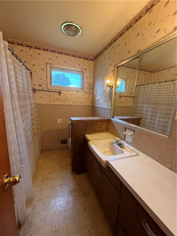 316 N 18th St, Lexington, MO 64067 - bathroom with wallpapered walls, vanity, tile walls, a shower with shower curtain, and wainscoting